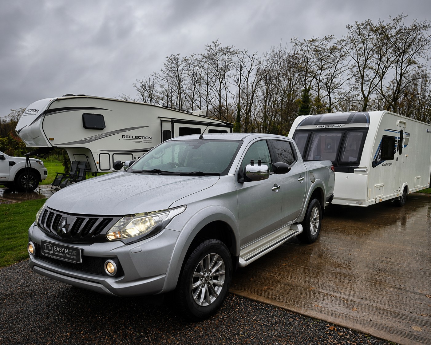 Pickup towing a caravan on a rainy caravan site